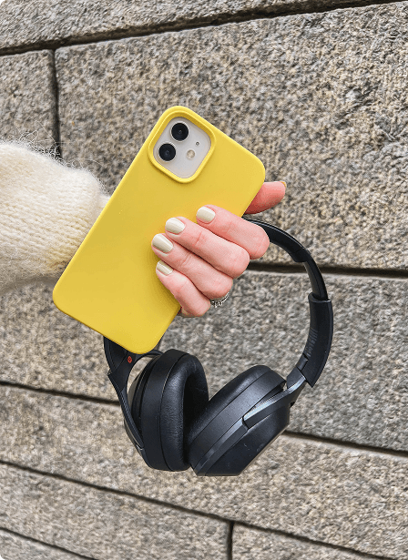 En hånd som holder en gul mobiltelefon og et headset